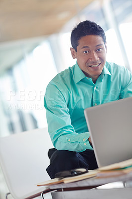 Buy stock photo Handsome young asian businessman using his laptop while at work