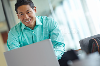 Buy stock photo Handsome young asian businessman using his laptop while at work