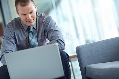 Buy stock photo A handsome young caucasian businessman working on his laptop