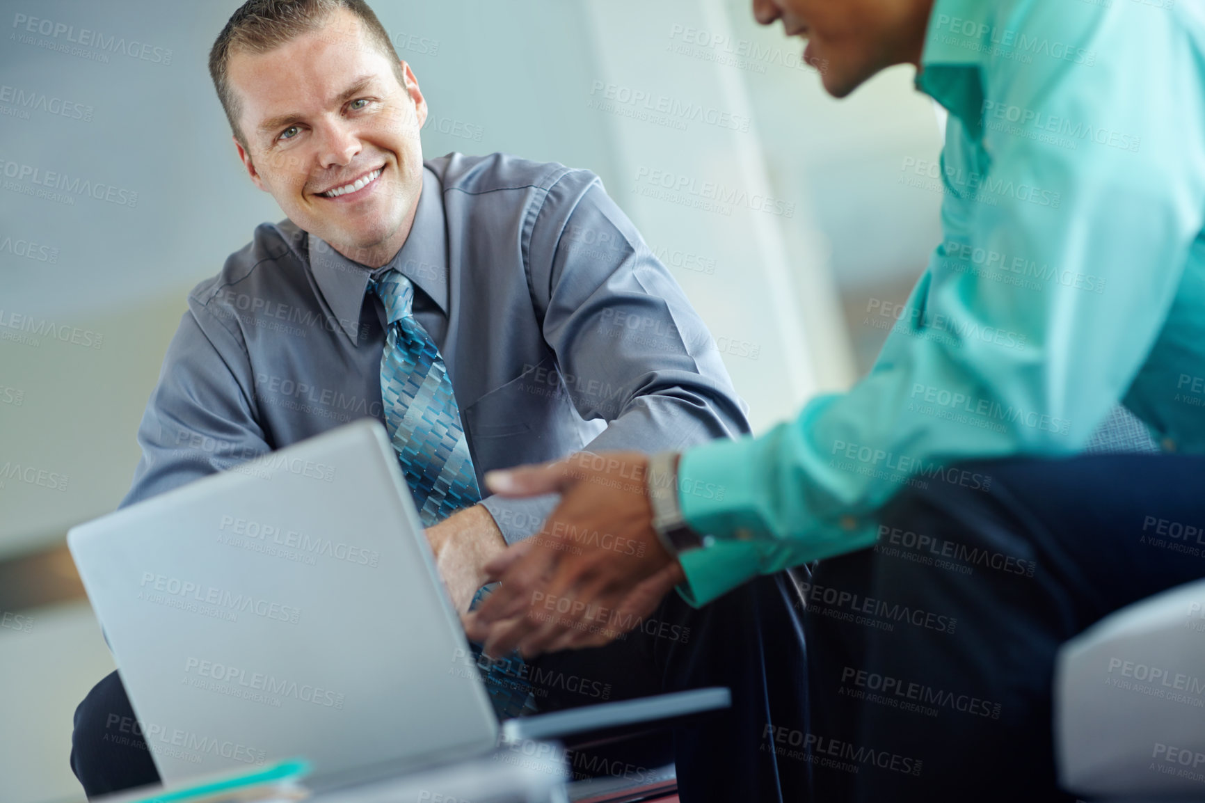 Buy stock photo Two handsome young businessmen working together while sharing a laptop between them