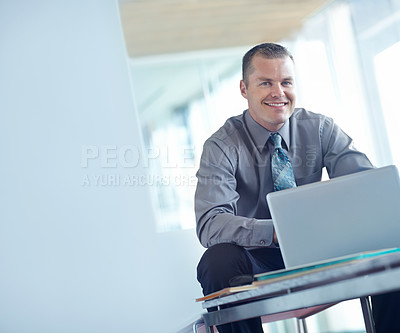 Buy stock photo A handsome young caucasian businessman working on his laptop