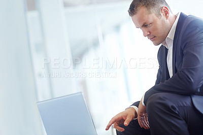 Buy stock photo A handsome young caucasian businessman working on his laptop