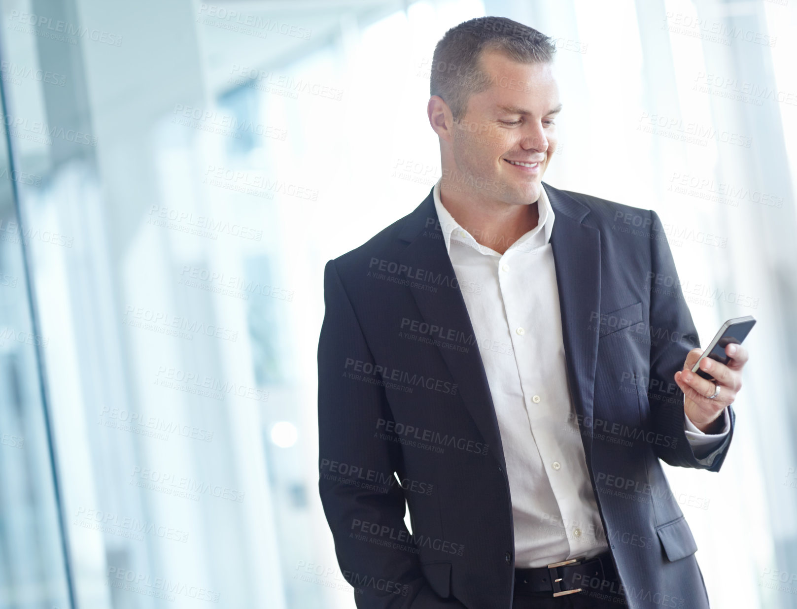 Buy stock photo A smiling caucasian businessman using a smartphone while working