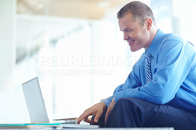 Buy stock photo A handsome young caucasian businessman working on his laptop