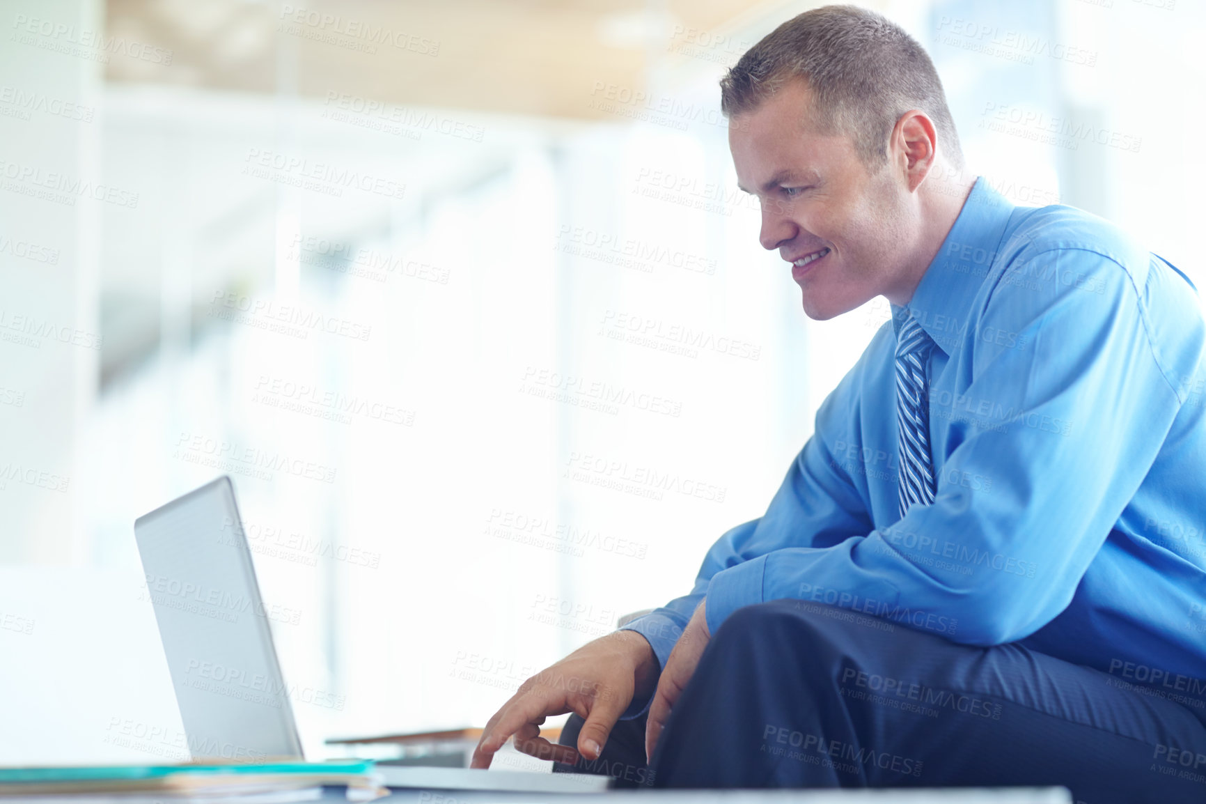 Buy stock photo A handsome young caucasian businessman working on his laptop