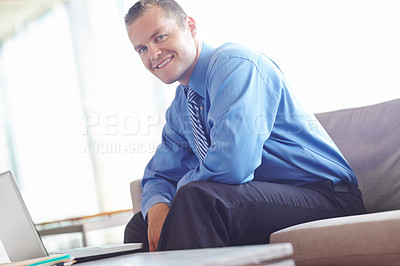 Buy stock photo A handsome young caucasian businessman working on his laptop