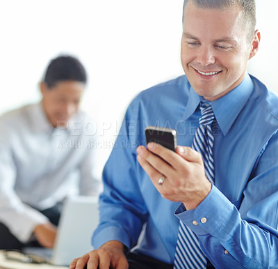 Buy stock photo A smiling caucasian businessman using a smartphone while working