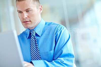 Buy stock photo A handsome young caucasian businessman working on his laptop
