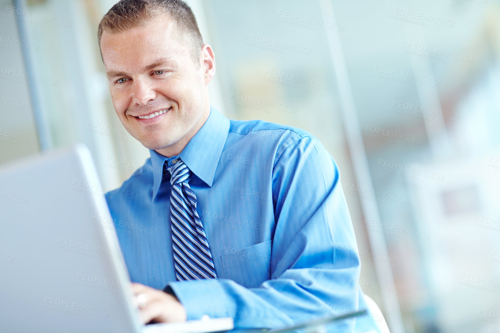 Buy stock photo A handsome young caucasian businessman working on his laptop