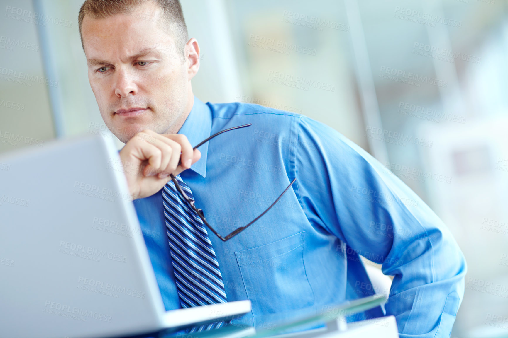 Buy stock photo Thoughtful young caucasian businessman working on his laptop 