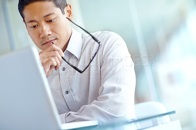 Buy stock photo Thoughtful young asian businessman working on his laptop 