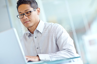 Buy stock photo Thoughtful young asian businessman working on his laptop 