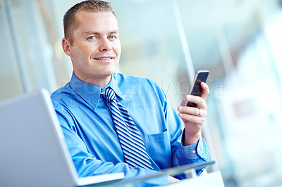 Buy stock photo Laptop, phone and portrait of employee man in lobby of office for communication or text message. App, business and social media with professional person in workplace for break or internet research