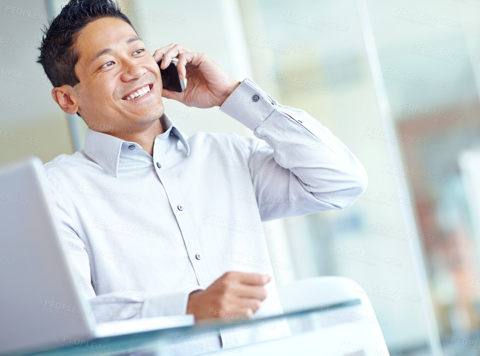 Buy stock photo A smiling asian businessman using his mobile while working