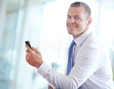 Buy stock photo A smiling caucasian businessman using a smartphone wile working