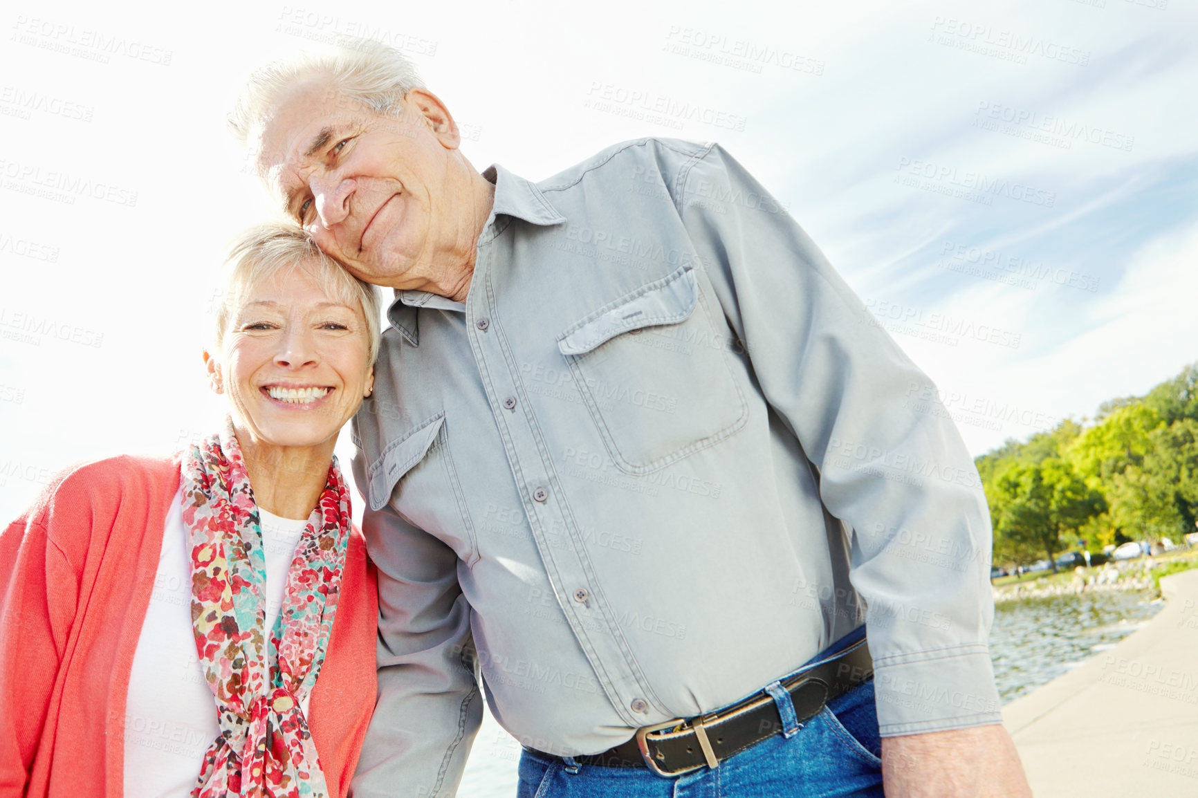 Buy stock photo A loving senior couple standing together next to a lake