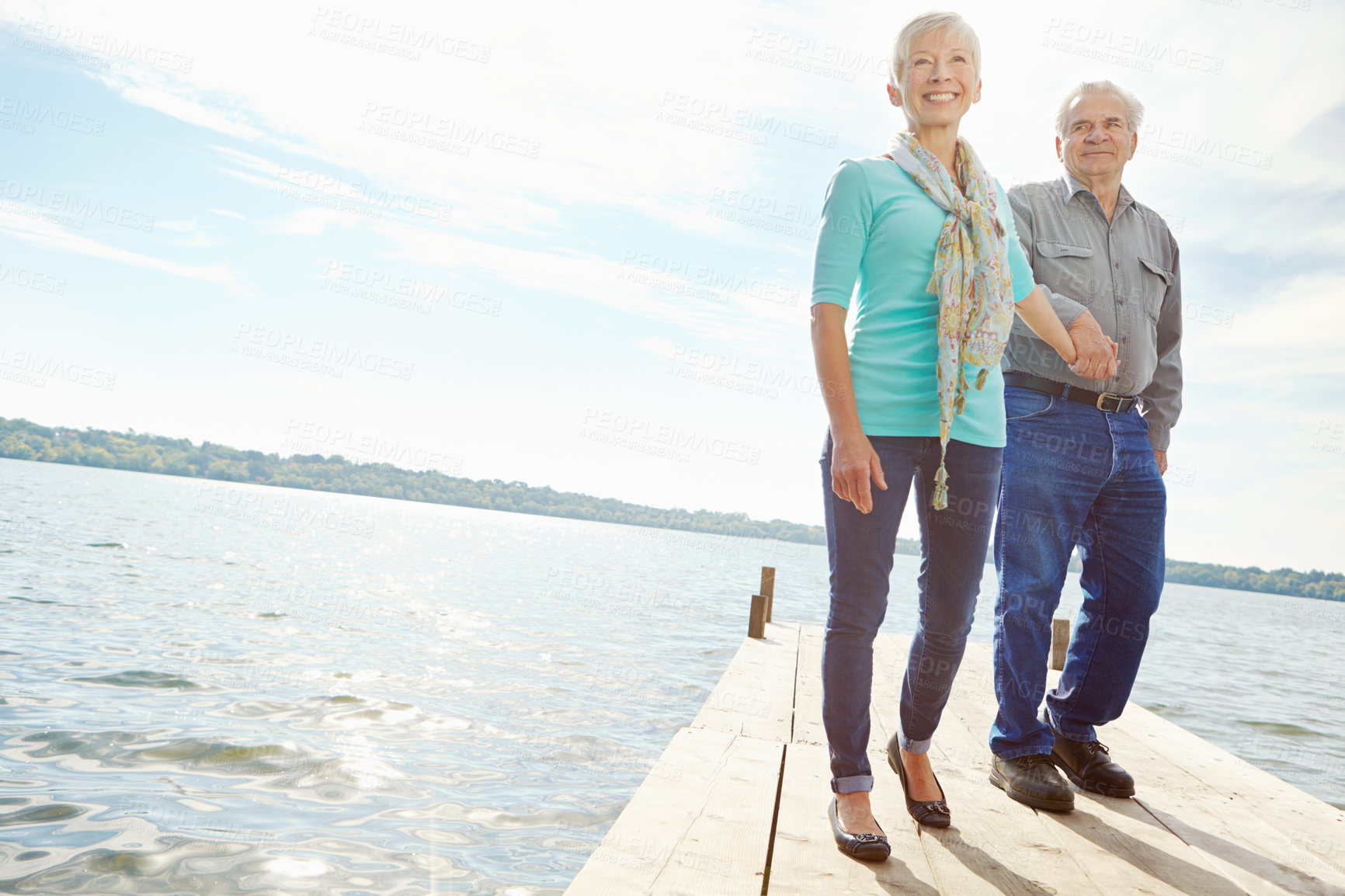 Buy stock photo Smile, senior couple and walk on pier outdoor for retirement, vacation and travel destination. Below, people and holding hands with marriage commitment, holiday location and bonding together on lake