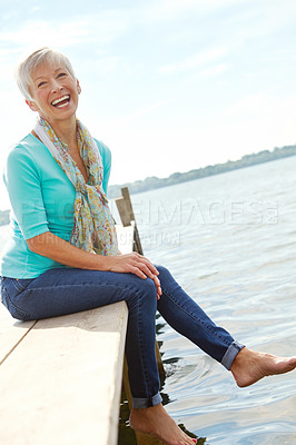 Buy stock photo An attractive mature woman sitting on the edge of the pier 