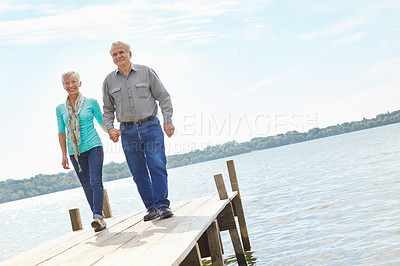 Buy stock photo A loving elderly couple wallking along the pier