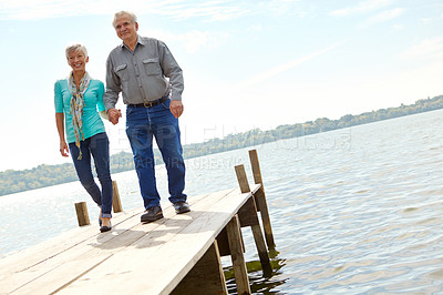 Buy stock photo An elderly couple walking along the jetty together