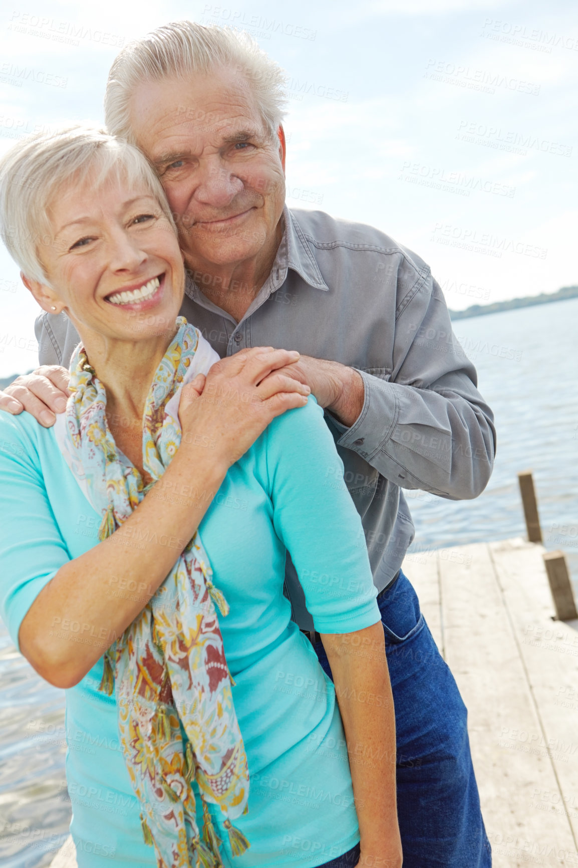 Buy stock photo Portrait of a senior couple embracing each other on a jetty