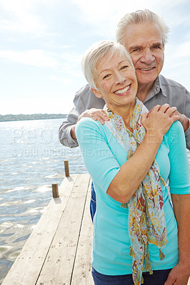 Buy stock photo A loving senior couple holding each other on a jetty 