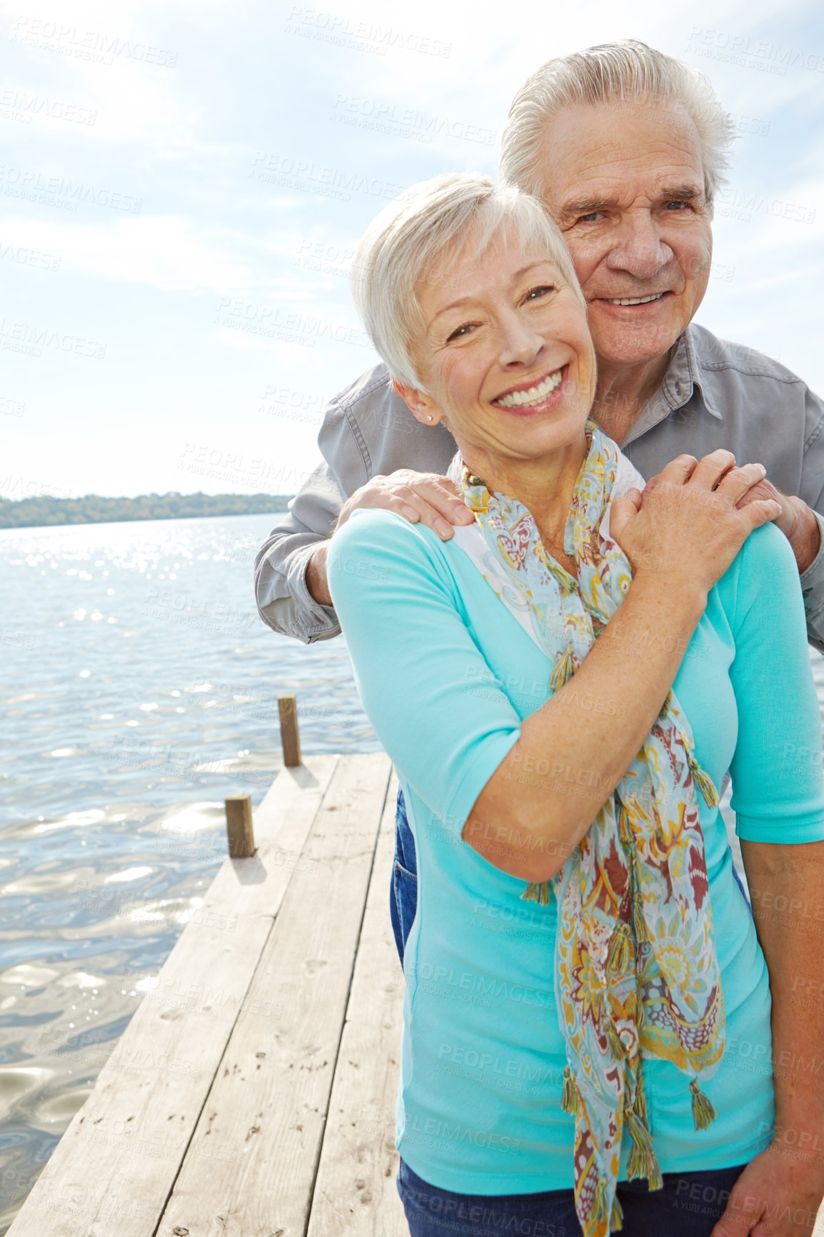 Buy stock photo A loving senior couple holding each other on a jetty 