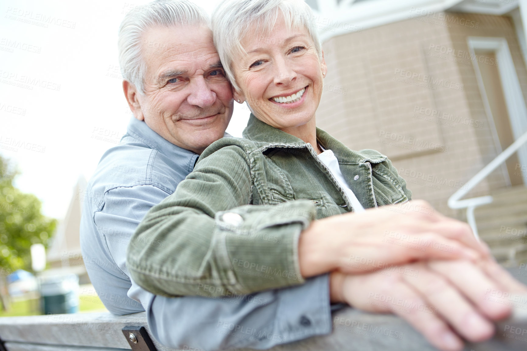 Buy stock photo A mature husband and wife cuddling together on a bench 