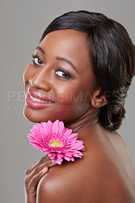 Buy stock photo Woman, skincare and flower in studio portrait with smile for results, cosmetics and change by grey background. Girl, model and African person with pink daisy for beauty, wellness and natural glow