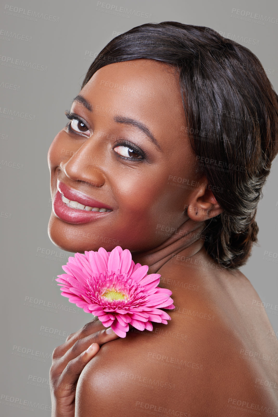 Buy stock photo Woman, skincare and flower in studio portrait with smile for results, cosmetics and change by grey background. Girl, model and African person with pink daisy for beauty, wellness and natural glow