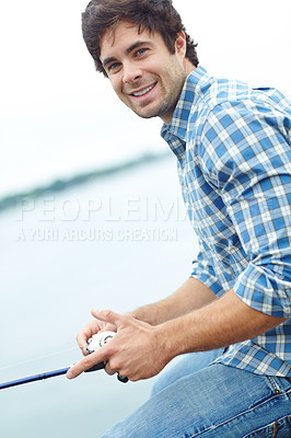 Buy stock photo A young guy sitting on the jetty and doing some fishing