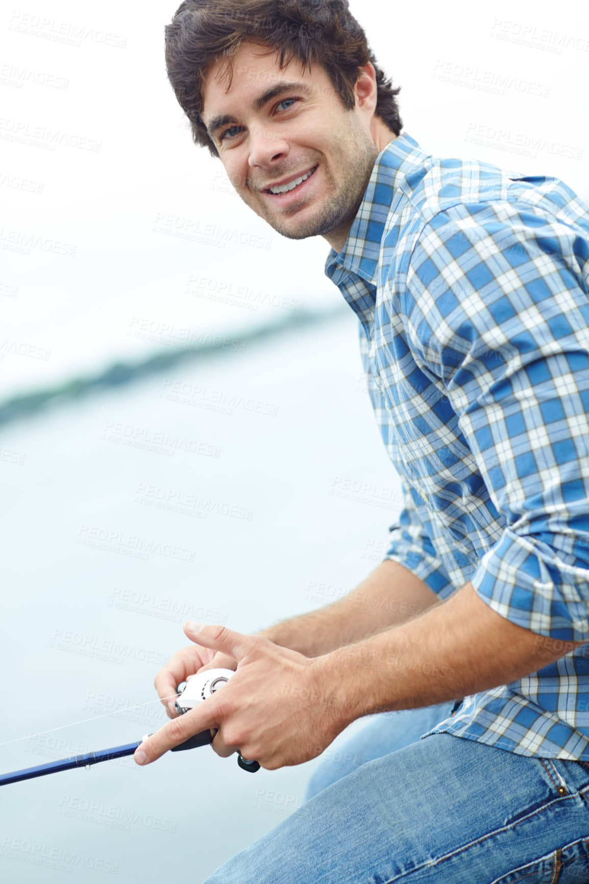 Buy stock photo A young guy sitting on the jetty and doing some fishing