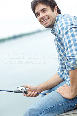 Buy stock photo A young guy sitting on the jetty and doing some fishing