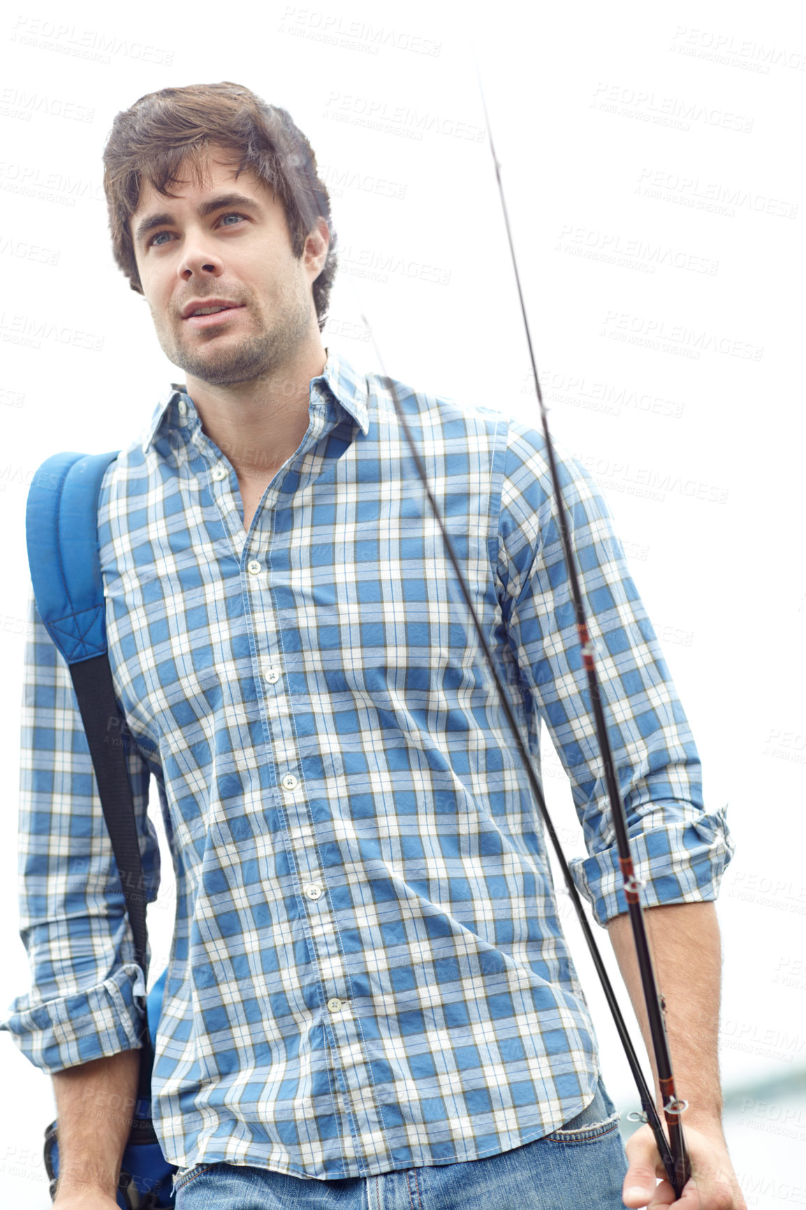 Buy stock photo A handsome young fisherman standing at the lake while carrying his gear