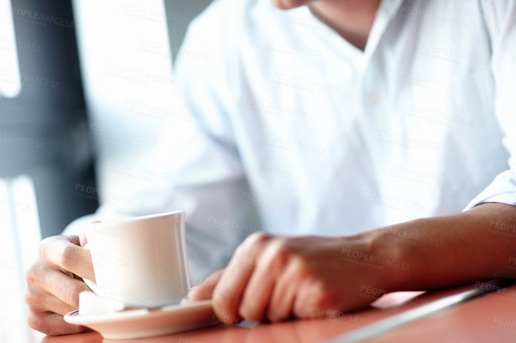 Buy stock photo Cropped image of a young man enjoying a cup of coffee in a restaurant