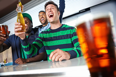 Buy stock photo Low view of a group of friends cheering on their favourite sports team at the bar