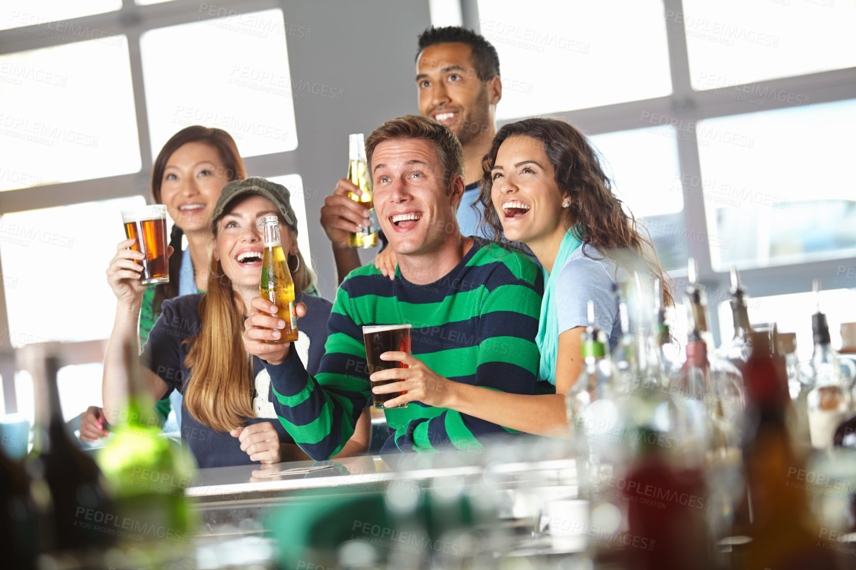 Buy stock photo A group of friends cheering on their favourite team at the bar