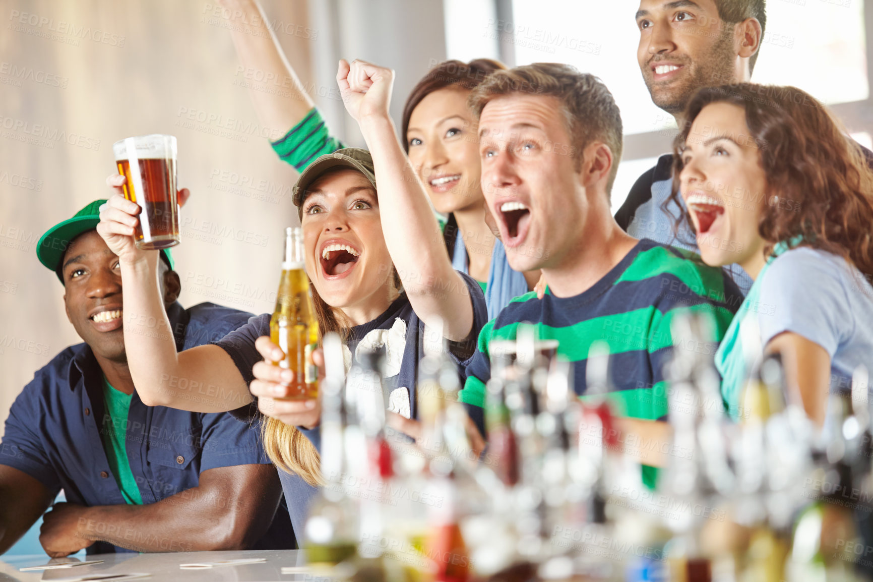 Buy stock photo A group of excited friends cheering on their favourite team at the bar