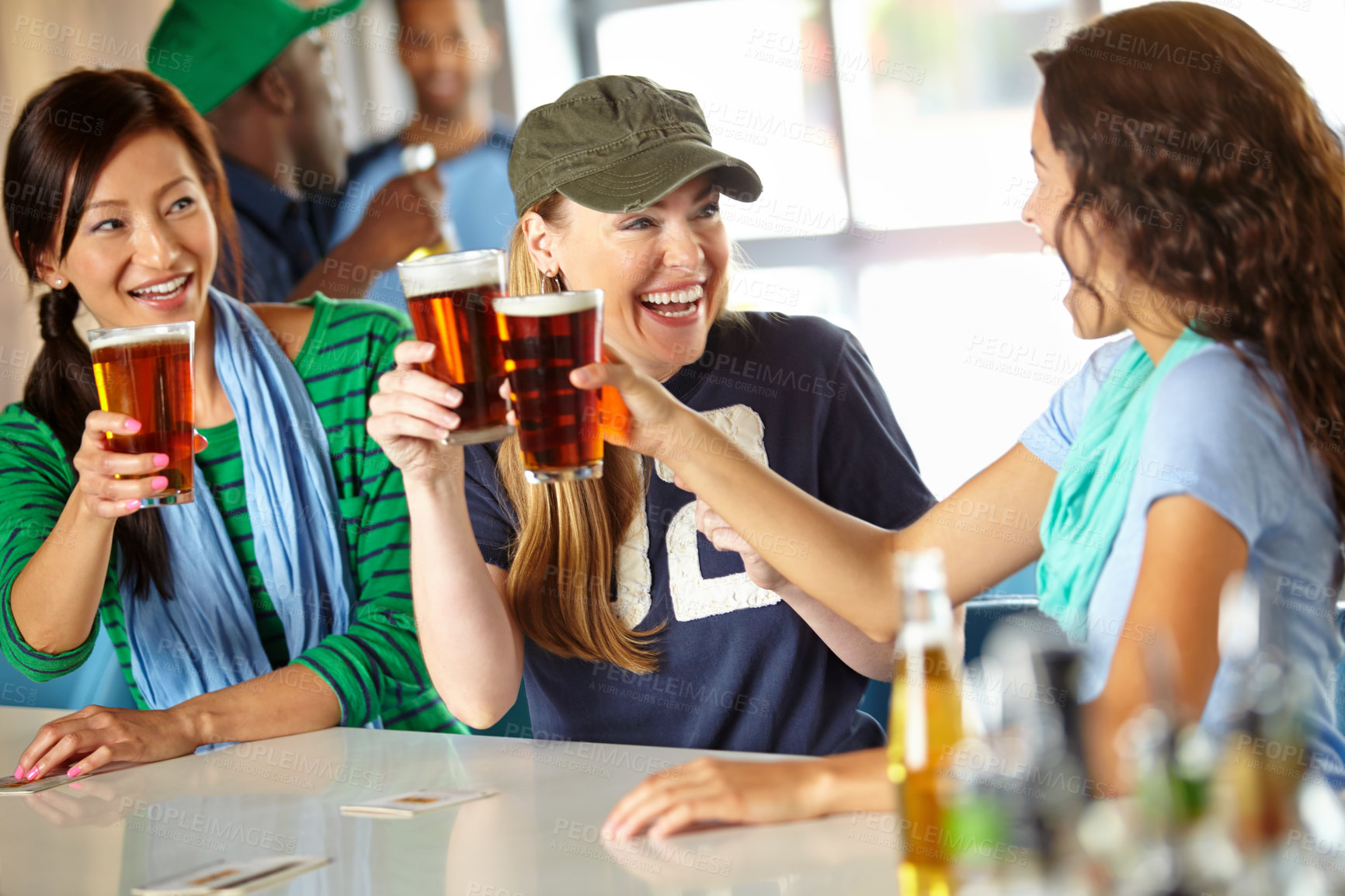 Buy stock photo Three girlfriends kicking back with a few drinks at the bar and watching sport