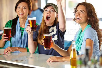 Buy stock photo Three girlfriends kicking back with a few drinks at the bar and watching sport