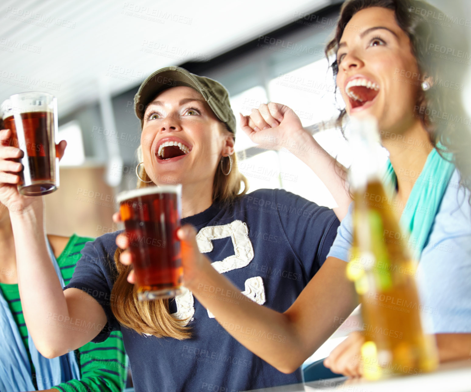 Buy stock photo Three girlfriends kicking back with a few drinks at the bar and watching sport