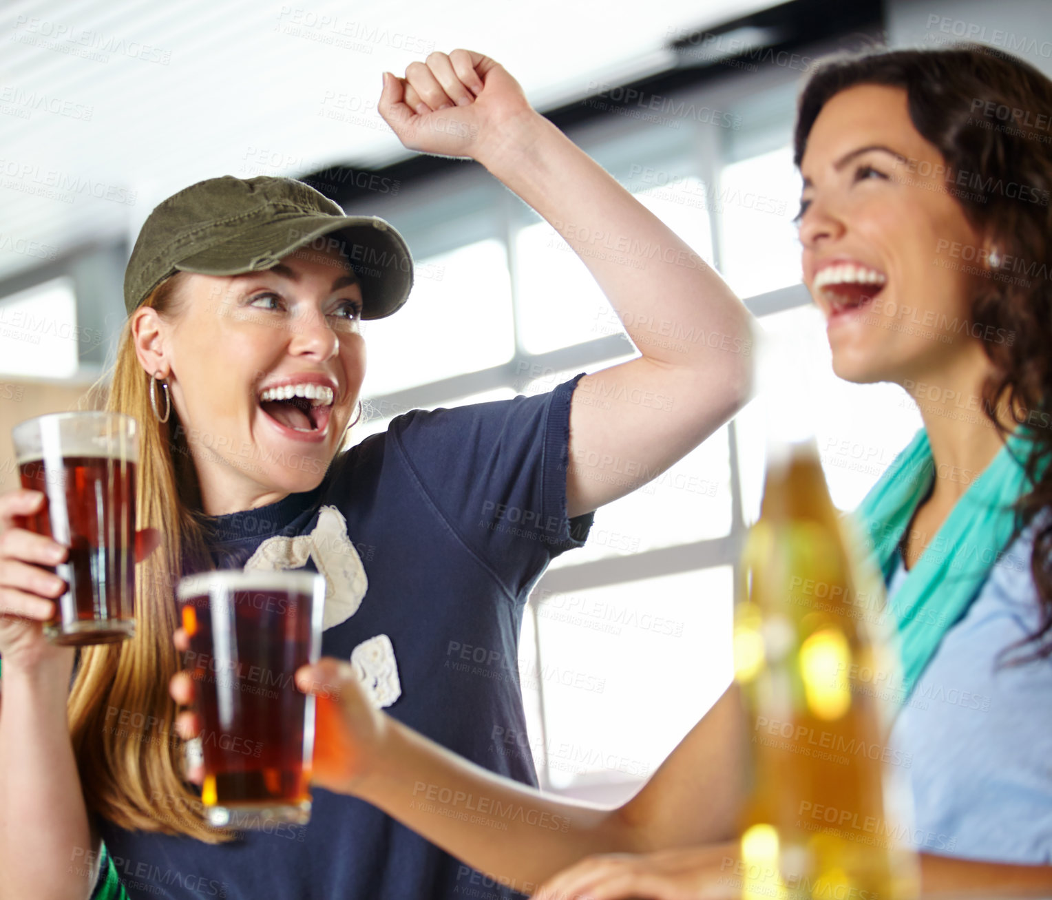 Buy stock photo A pretty woman looking at her girlfriend while enjoying drinks and watching sport at the bar