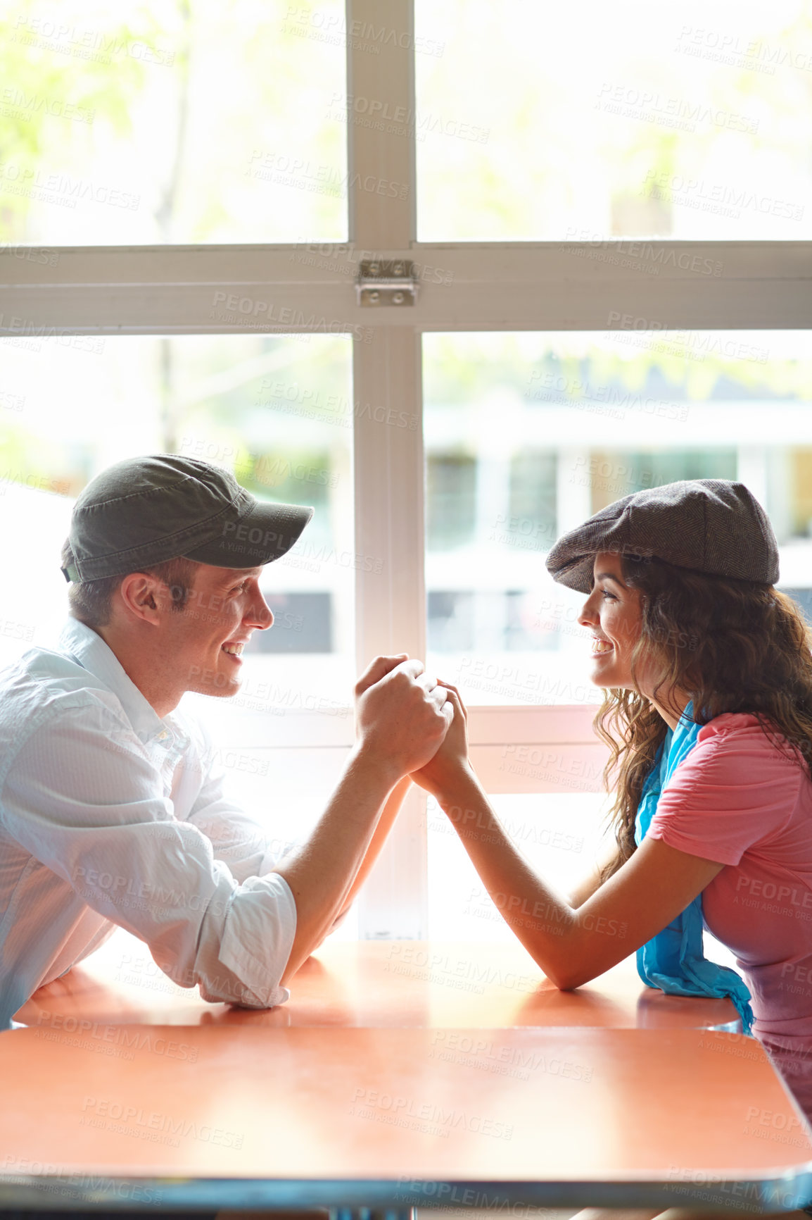 Buy stock photo A young couple holding hands and looking at one another in a restaurant