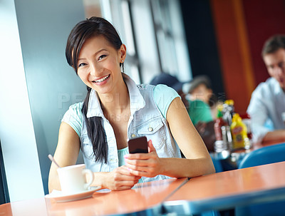 Buy stock photo Portrait of a pretty woman holding her smartphone in a coffee shop