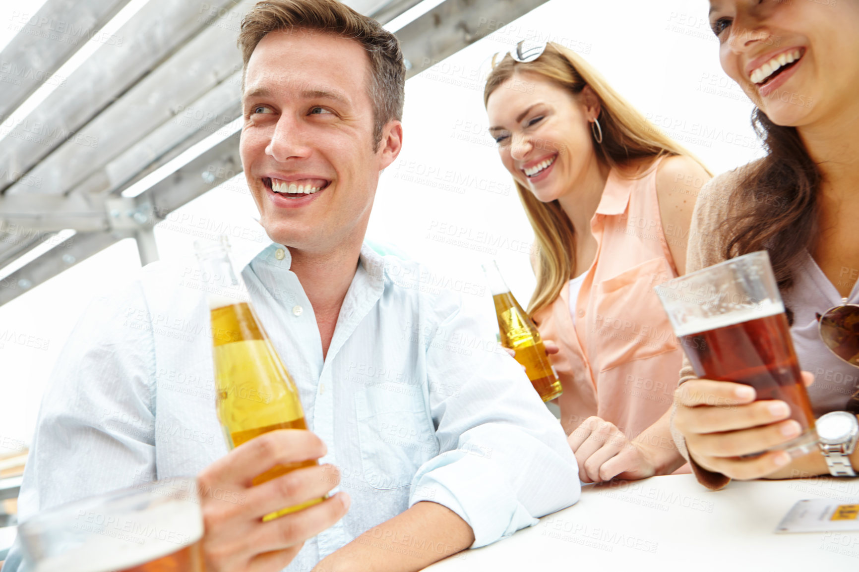 Buy stock photo A handsome guy enjoying drinks with his friends on the deck of a popular restaurant