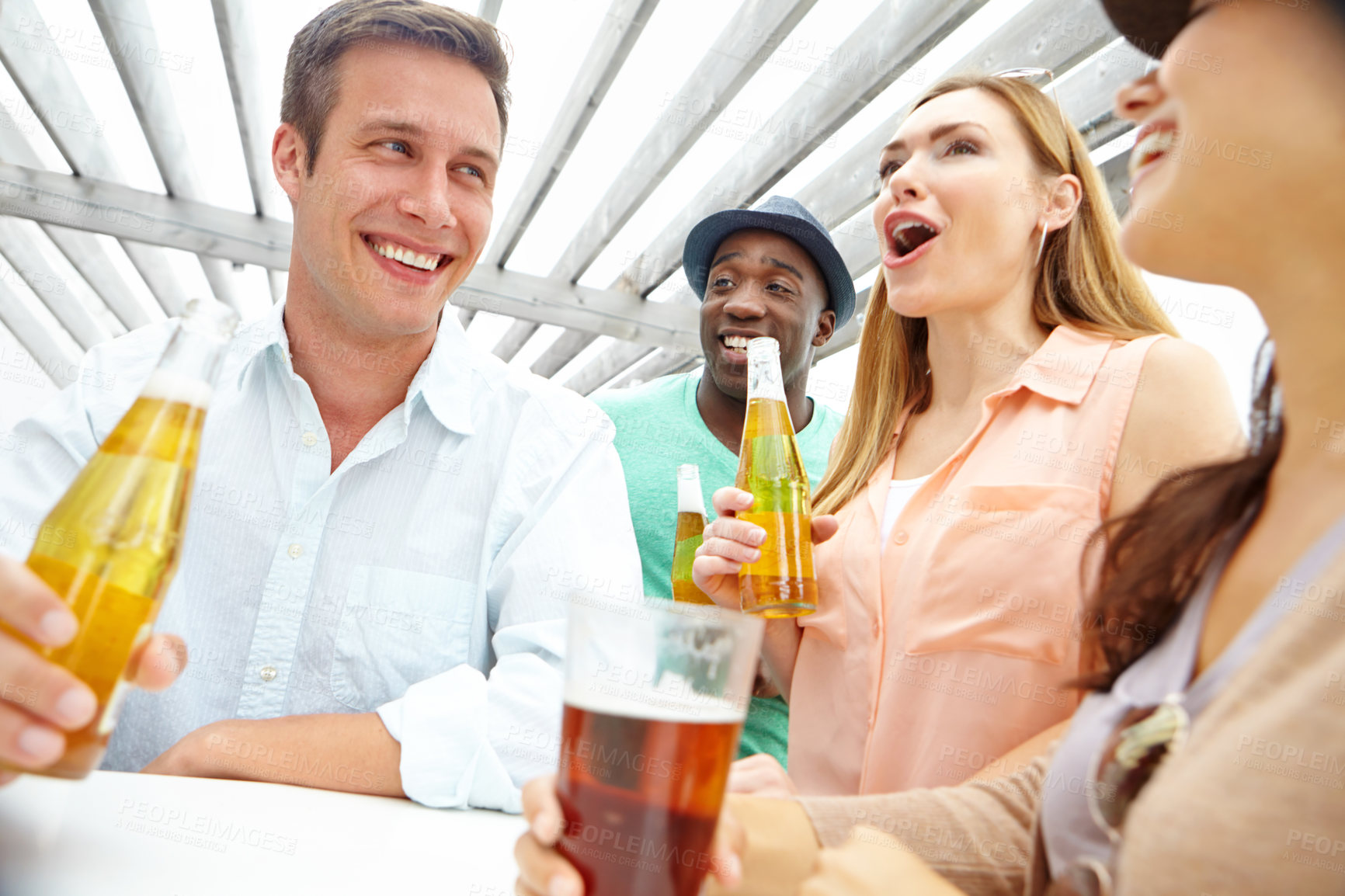 Buy stock photo A handsome young man enjoying drinks on the outdoors deck of a restaurant with friends