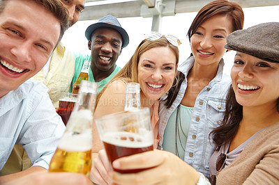 Buy stock photo Portrait of a young group of friends clinking their drinks together at a restaurant