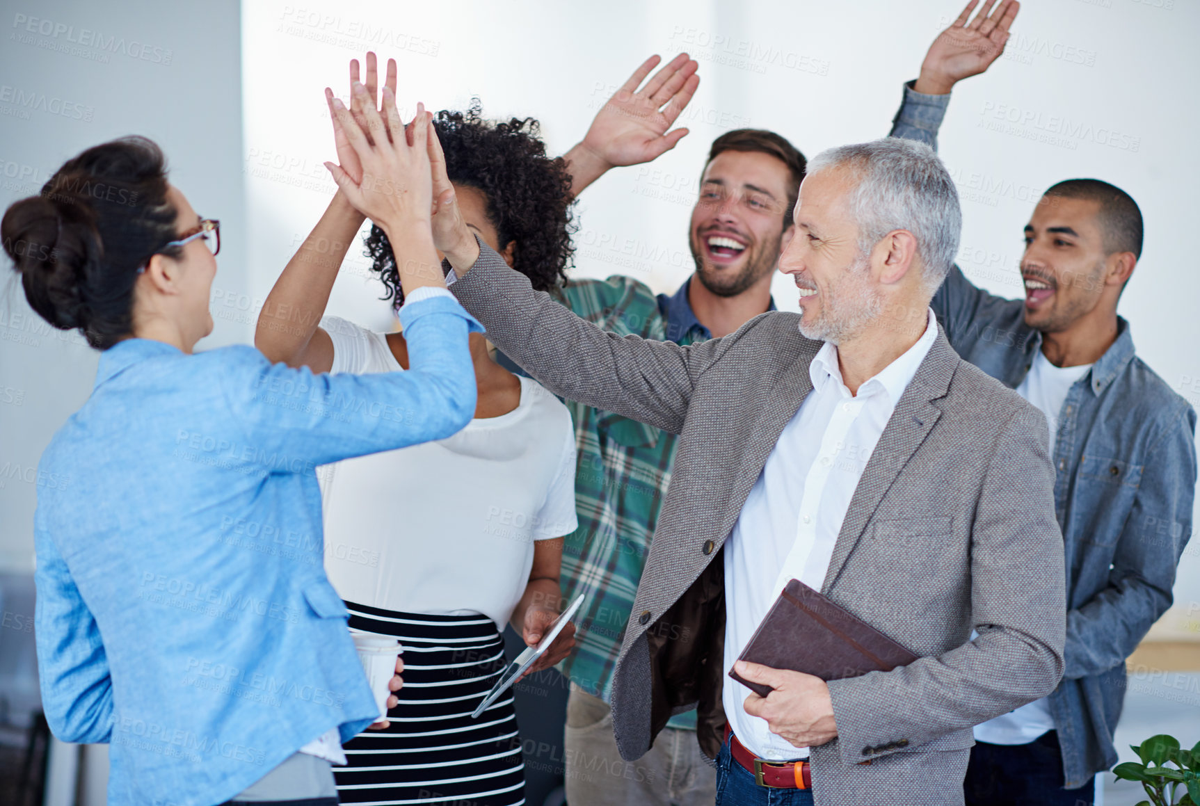 Buy stock photo Shot of a group of happy coworkers high-fiving while standing in an office