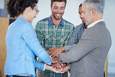 Buy stock photo Shot of a group of happy coworkers standing with their hands together in huddle in an office