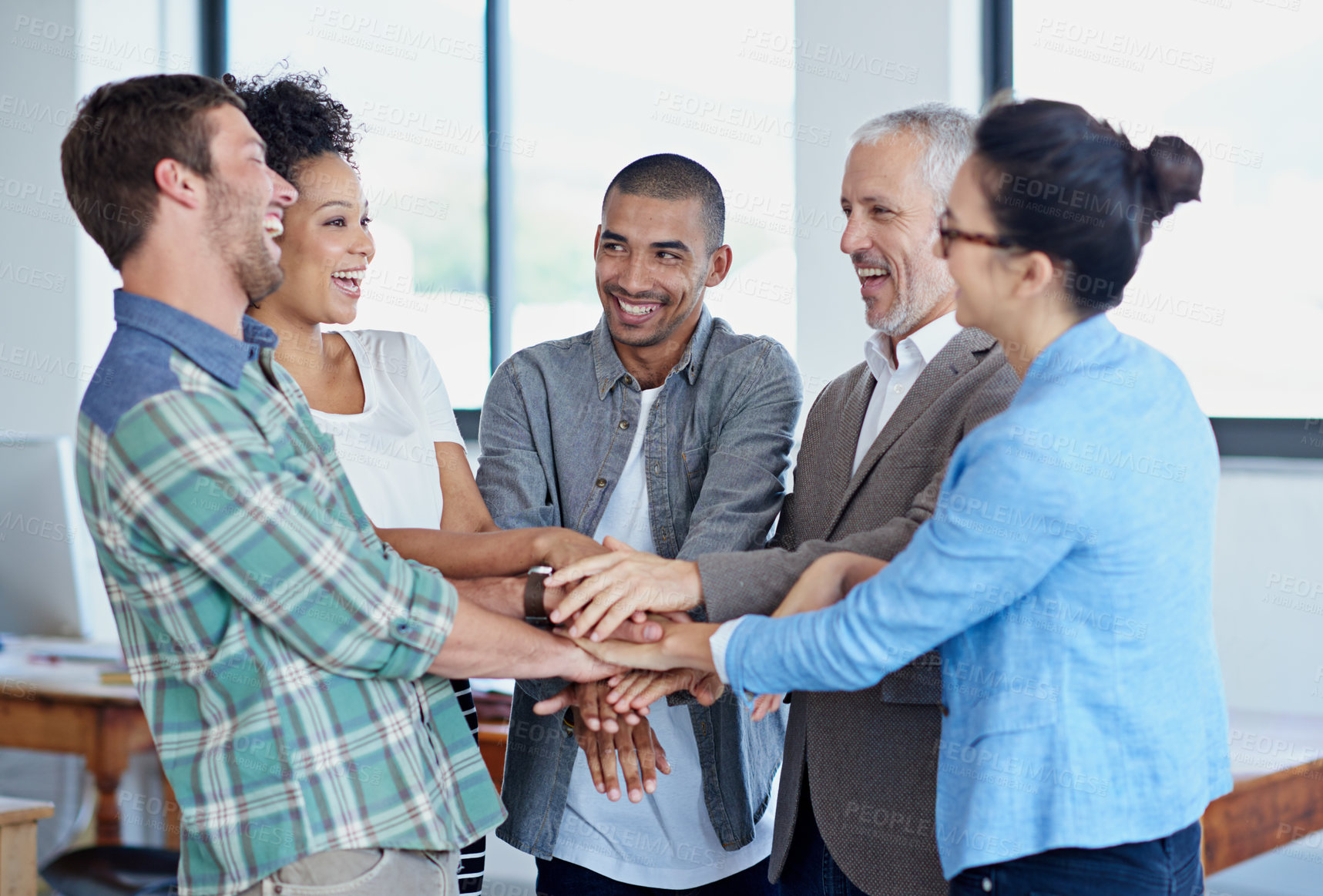 Buy stock photo Shot of a group of happy coworkers standing with their hands together in huddle in an office